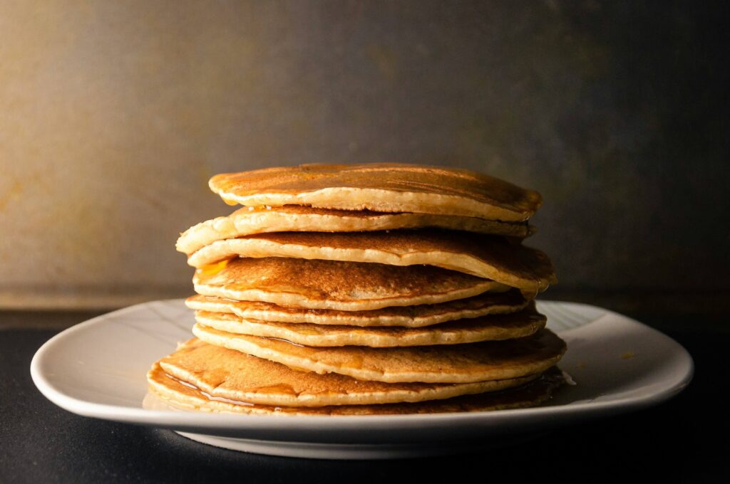 Fluffy green pancakes garnished with sliced scallions on a plate.