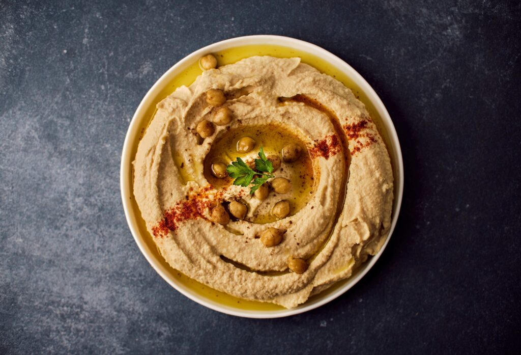 Creamy hummus topped with olive oil, chickpeas, and herbs in a ceramic bowl