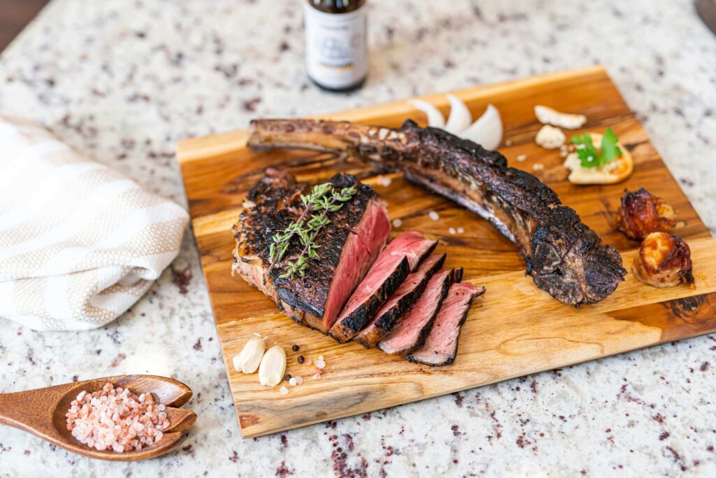 Slicing grilled steak for chimichurri bowl on a cutting board with fresh ingredients.